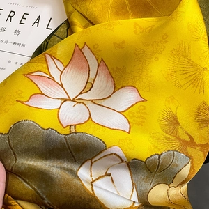 Close-up of silk scarf featuring elegant yellow lotus prints and soft texture