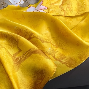 Detailed macro view of yellow silk scarf with traditional pine, butterfly and flower prints