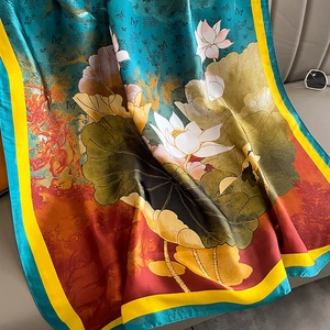 Elegant silk-like scarf with lotus flower art draped on a sofa for a stylish winter look