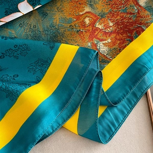 Detailed view of dark green silk scarf with floral patterns and yellow borders