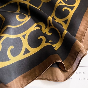 Detailed macro view of luxurious gold baroque patterns on a silky dark grey scarf