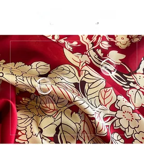 Détail du tissu en soie artificielle rouge avec imprimés floraux et éclat satiné