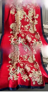 Détail d'une écharpe en soie rouge avec imprimé floral et finition de bord soignée