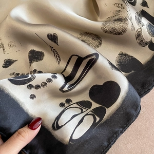 Détail d'un foulard en soie champagne avec motifs dessinés et bords roulés