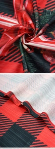 Close-up of Christmas red buffalo plaid fabric texture with pine branch and ball prints