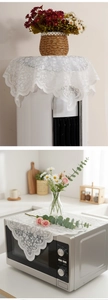 Detail of white floral lace dust cover with scalloped edges for microwave or nightstand