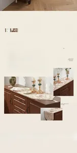 Detail of cream table runner with floral embroidery and tassels on wooden cabinet
