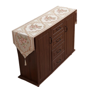 European style table runner with pink floral patterns and tassels on a wooden cabinet