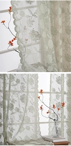 Detail of light green floral embroidery and elegant scalloped edges on sheer lace curtain
