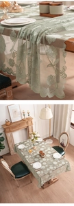 Detail of sage green embroidered lace tablecloth with floral patterns and scalloped edges