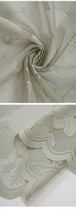 Detail of grey-green lace curtain with floral embroidery and scalloped edges