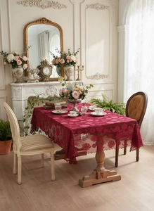 Detail of dark red vintage lace tablecloth featuring intricate floral hollow embroidery