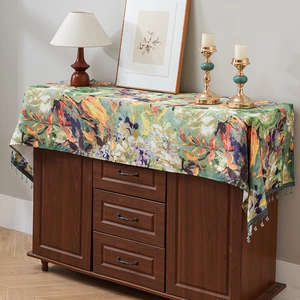 Vintage floral table runner with beaded fringe tassel on dark wooden cabinet