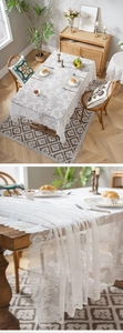 Close-up of white rectangular lace tablecloth with elegant floral embroidery and wavy edges