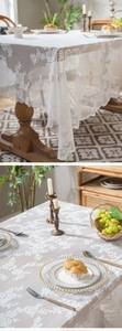 Detailed view of white lace tablecloth featuring floral hollow patterns and scalloped edges
