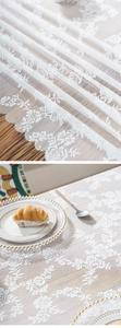 Detail of white floral lace tablecloth with scalloped edges and elegant rose patterns