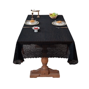Modern black geometric lace tablecloth with wavy scalloped edges on wooden dining table
