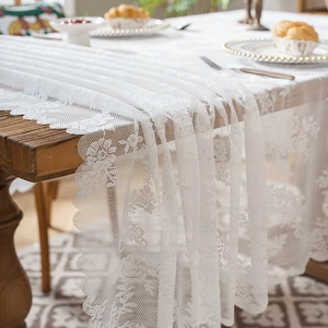 Elegant white floral lace tablecloth with scalloped edges on a wooden dining table