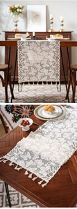 Detailed close-up of white lace table runner with butterfly patterns and tassel edges