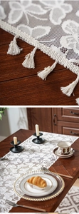 Detail of white lace table runner with hollow floral pattern and elegant fringe trim