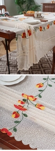 Detail of cream lace tablecloth with elegant tulip embroidery and scalloped edges