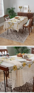 Close-up of yellow floral embroidery on beige lace tablecloth with hollow-out texture