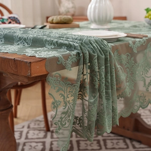 Sage green French lace tablecloth with vintage floral patterns on a wooden table