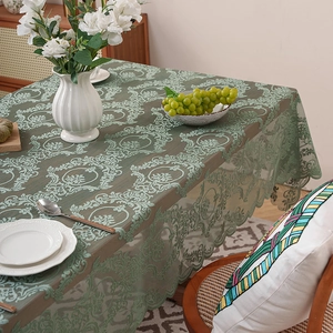 Vintage dark green lace tablecloth with damask patterns on a wooden dining table