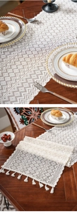 Detail of cream crochet table runner with geometric diamond patterns and fringe tassels