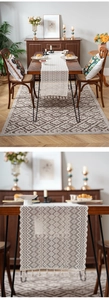 Close-up of geometric knit patterns and handmade tassels on an off-white table runner