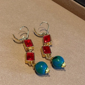 Detail of vintage long earrings with red square crystals and blue marble bead
