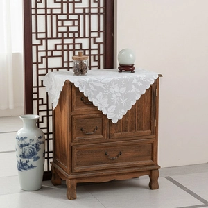 White floral lace tablecloth with scalloped edges on a vintage wooden cabinet top