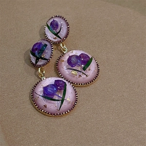 Close-up of pink resin earrings with dried flowers, gold leaf flakes and gold bead edge
