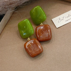 Detail shot of green and amber resin square earrings with gold metal connectors