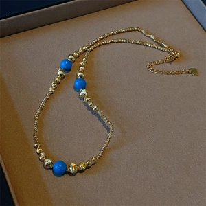 Detail of beaded gold necklace featuring turquoise accents and a heart charm extension