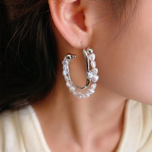 Détail de la boucle d'oreille double couche en C avec perles blanches et pierre zircon