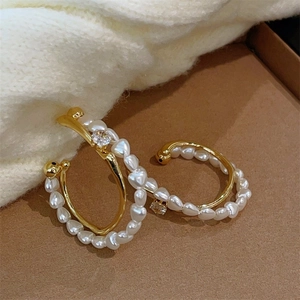 Gros plan de boucles d'oreilles C dorées avec perles irrégulières et zircones