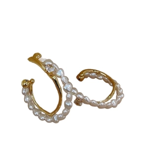 Boucles d'oreilles double couche dorées avec perles et zircons sur fond blanc