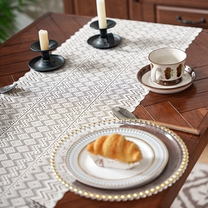 Lace hollow table runner with geometric diamond pattern on a dark wood dining table