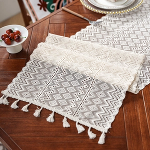 Beige knitted lace table runner with geometric crochet patterns and tassel fringe decor