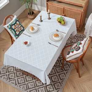 Tovaglia bianca con jacquard geometrico a quadrifoglio e bordo smerlato sul tavolo