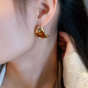 Macro shot of French retro amber resin heart earrings on model with gold texture