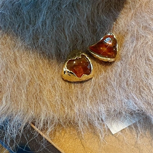 Macro view of vintage heart-shaped amber resin earrings with hammered gold-tone metal edges