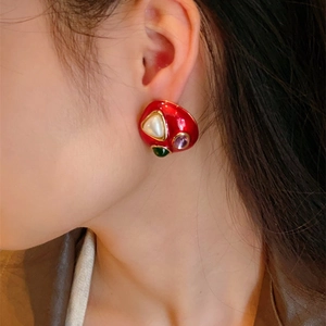Detail of vintage red enamel earring with baroque pearl and colorful gemstone inlays