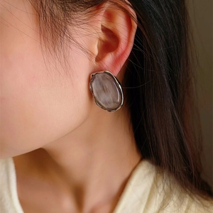 Irregular silver-edged oval resin earrings with grey-purple cat eye texture on model