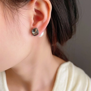 Detailed close-up of French square crystal stud earrings with large white pearls worn on ear