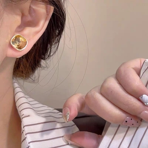 Close-up of square amber gemstone earrings with gold trim on a model ear