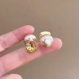 Macro shot of French style square yellow gemstone and champagne pearl earrings for women