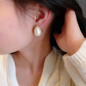 Elegant water drop pearl earrings with marble texture and gold trim on female model