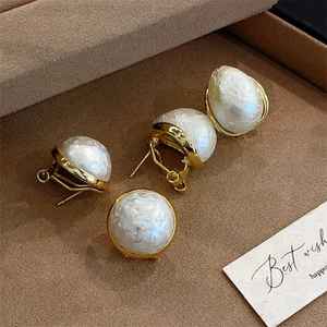 French vintage style pearl stud earrings with textured gold metal frames on velvet tray